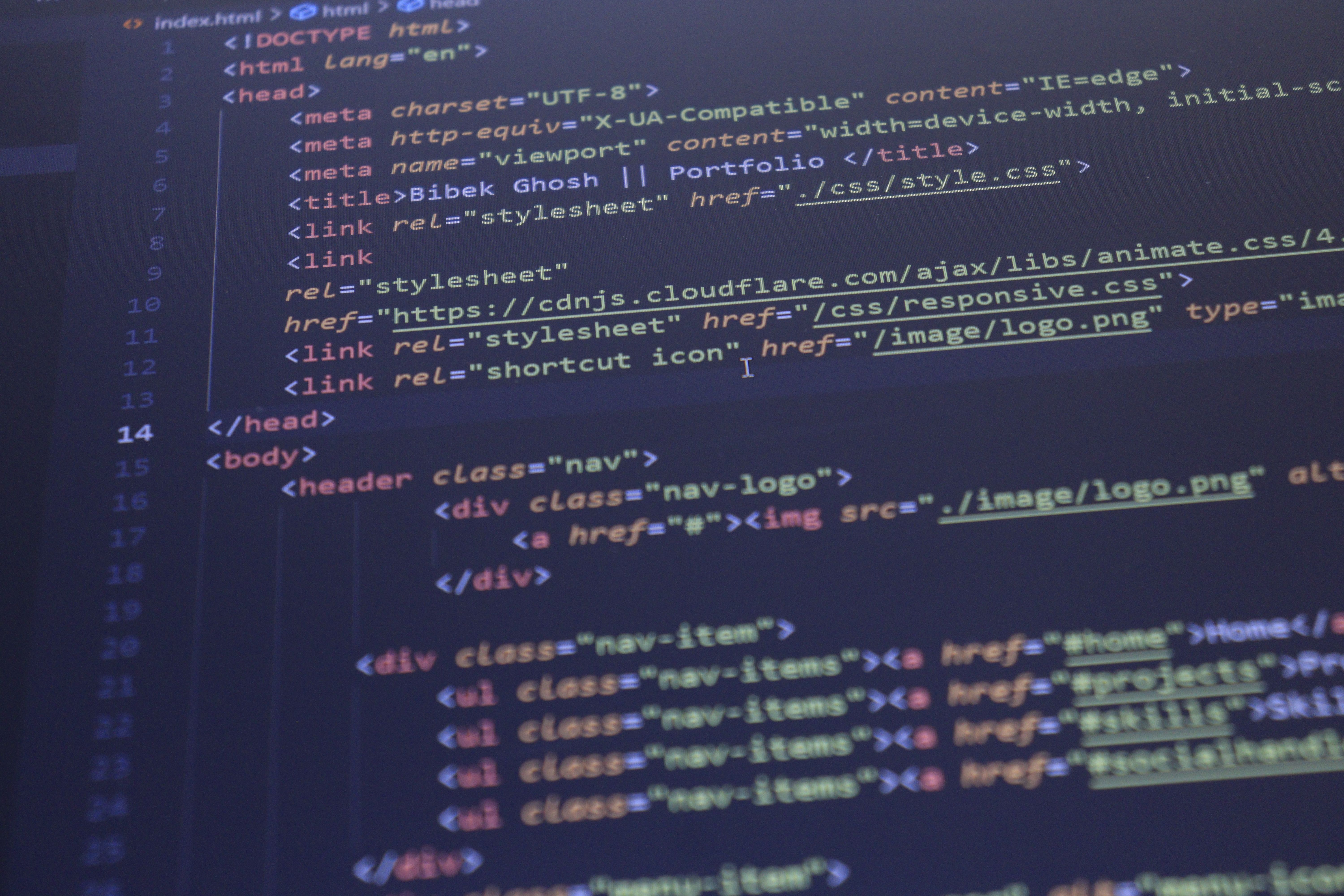 A monitor displaying colorful HTML code for a website in a dark-themed text editor